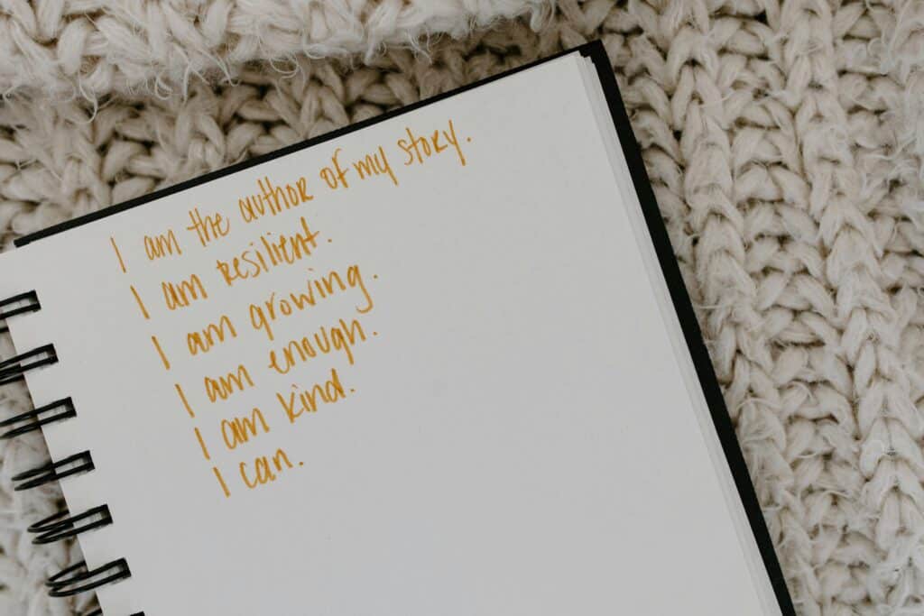 Affirmations Notebook with handwritten affirmations on knitted fabric background.