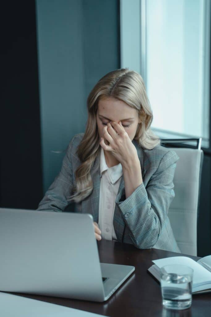 Businesswoman showing stress at her desk with a laptop, highlighting work pressure from narcissistic boss