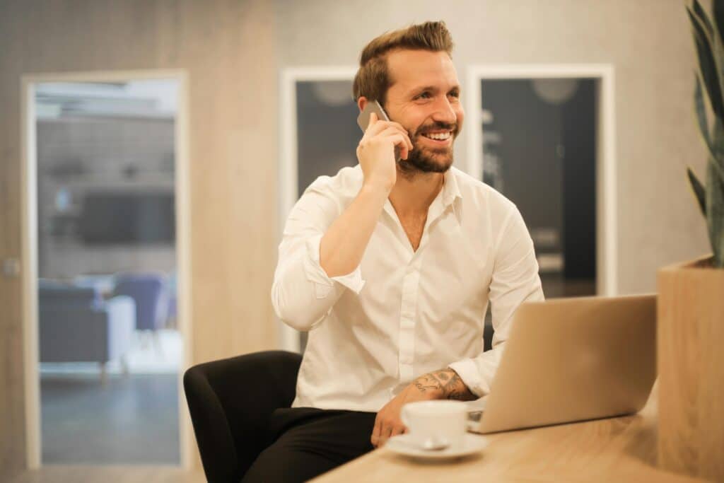 Happy businessman in office talking on phone with his therapist for entrepreneurs & business owners