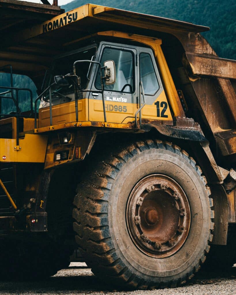 Close-up of a large yellow dump truck used in mining, highlighting its robust build and giant wheels.