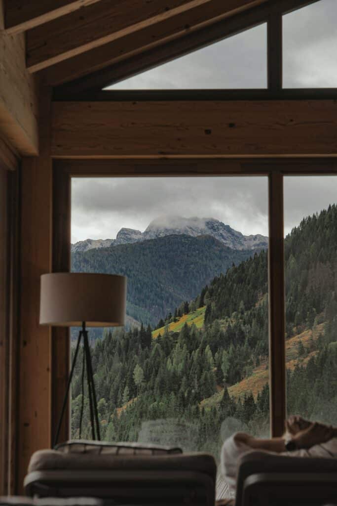Stunning mountain landscape seen through a modern window with lamp indoors.
