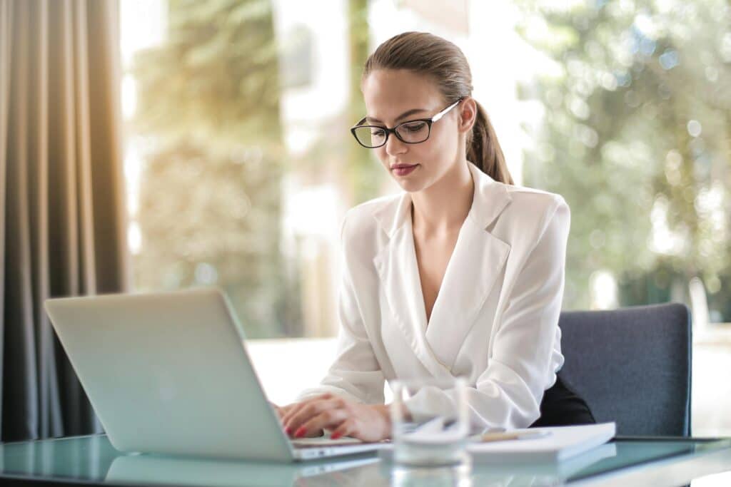 Confident businesswoman using a laptop at her desk, focused on her work symbolizing how even high functioning professionals can become victims of workplace emotionally abusive coworkers