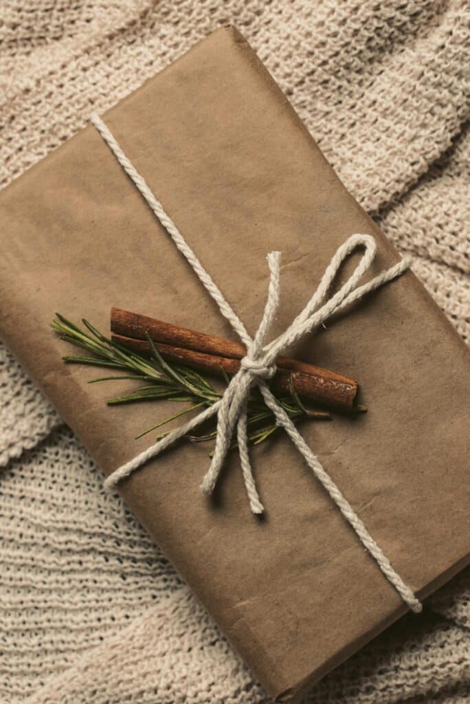 A cozy, eco-friendly gift box wrapped in brown paper and twine, adorned with rosemary and cinnamon.