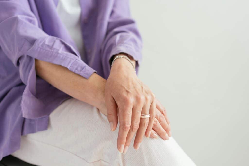 A close-up of a woman's hands gently resting on her lap, showcasing a sense of calm and elegance.