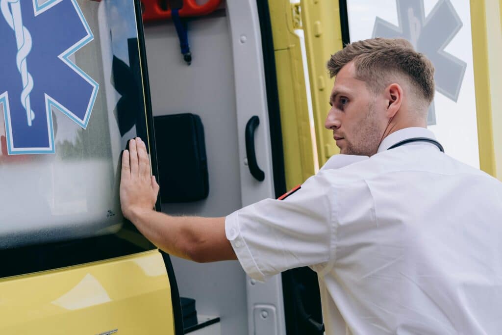 Emergency medical technician securing ambulance door, focusing on readiness.