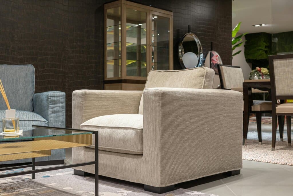 Interior of cozy light living room with comfortable armchairs near table with glass tabletop near cabinet